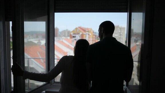 一对年轻夫妇在他们新家的阳台上做着白日梦