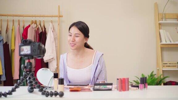 美妆博主坐在镜头前拍摄美妆视频快乐美丽的年轻亚洲女子用化妆品点评化妆教程在社交网络直播