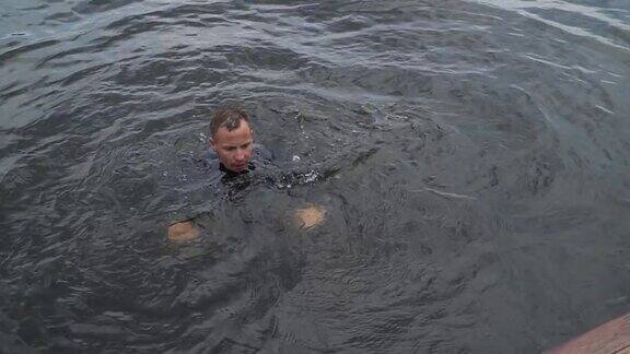 一个穿着潜水服的年轻人正在河里游泳