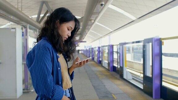 一名年轻女子在站台上浏览智能手机