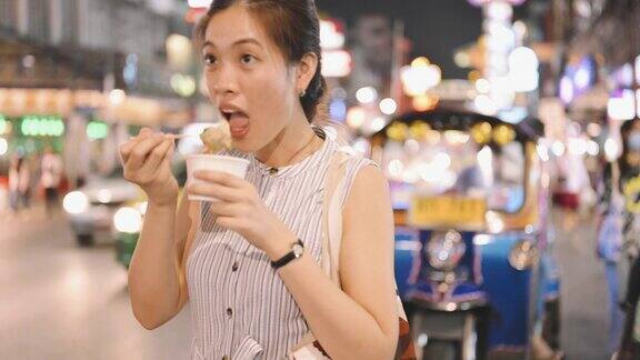 在泰国曼谷唐人街的瑶华路当地的亚洲女游客喜欢在晚上吃冰淇淋和自拍