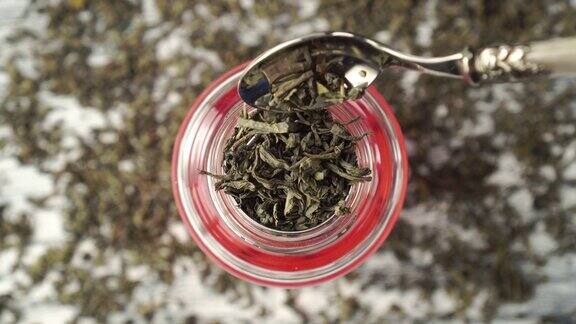 绿茶干燥的卷叶落入玻璃茶壶特写