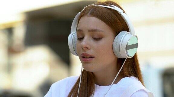哭泣的少女在户外戴着耳机听音乐