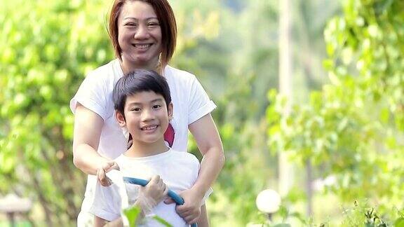 亚洲母亲和儿子正在浇树