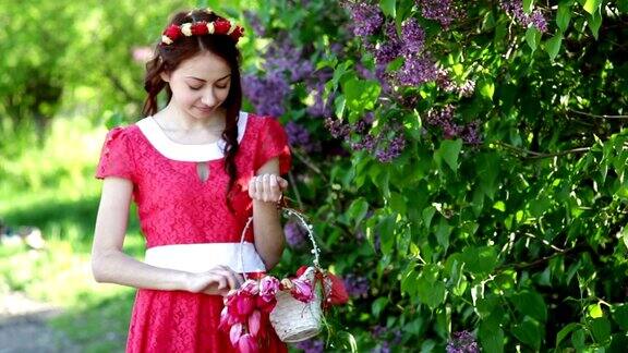穿着红衣服的漂亮女人在公园的丁香花丛中漫步