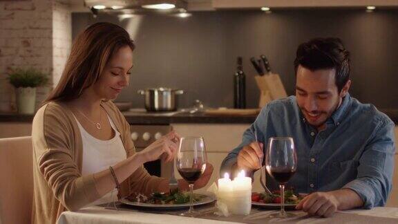 一对美丽的夫妇在厨房里吃烛光晚餐他们吃喝聊天两个都有好心情和微笑很多结束运动