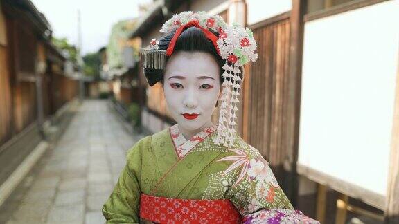 舞妓(正在训练的艺妓)站在京都祗园狭窄的小路上