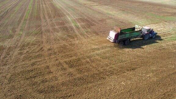 一辆拖拉机在农场附近的田地上施有机肥给土壤施肥以获得更好的收成前视图