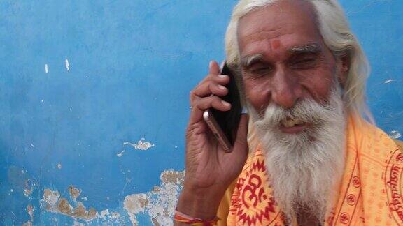 手持特写的印度苦行徒微笑而在他的手机上接听电话