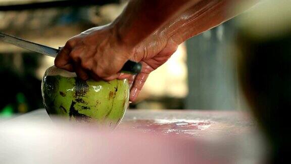 一个男人用一把大刀切开椰子