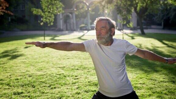 一位白发老人在公园里健身他的手臂总是向不同的方向伸展
