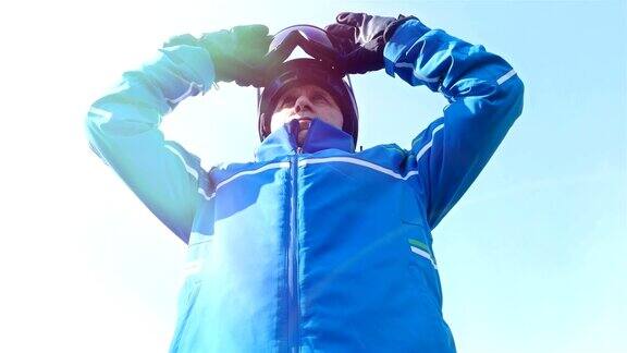 低角度的男性滑雪者把他的眼镜放在蓝色的天空