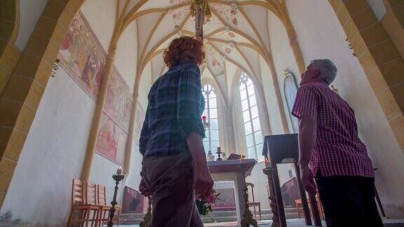 一对老夫妇来到教堂祭坛天花板上挂着十字架