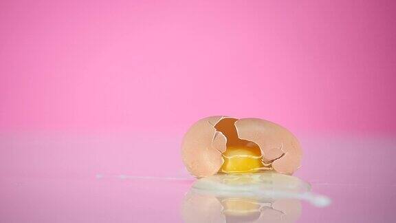 鸡蛋掉了下来撞在粉红色的背景上