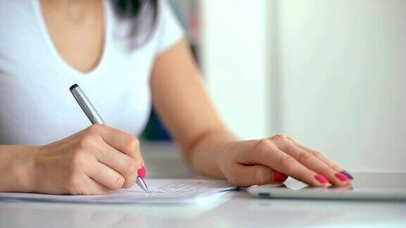 女性用钢笔在笔记本上写字