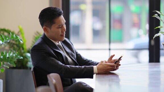 亚洲商人使用智能手机与合作伙伴交谈