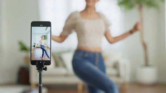 一位亚洲年轻女子用智能手机摄像头制作了她的舞蹈视频分享视频到社交媒体应用程序