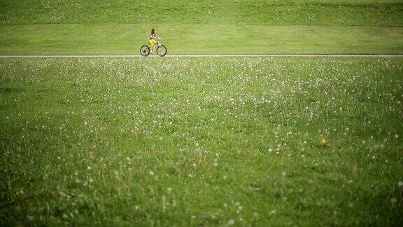 小女孩骑着粉红色的自行车在公园里骑车