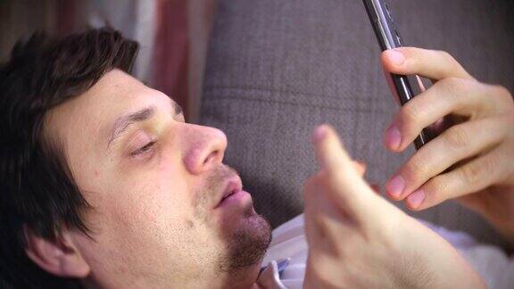 一名男子躺在沙发上用手机发信息然后睡着了