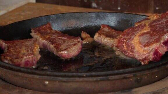 在铁锅里煎牛排这家餐厅的专业厨师在家做饭厨师把一块肉放在火上烤煎烟生肉蒸煮过程