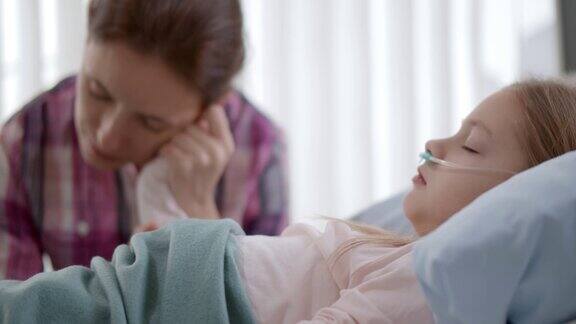 母亲牵着躺在病床上熟睡的孩子的手