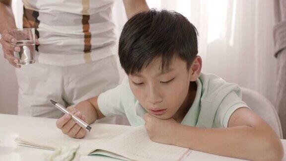 亚洲父亲站着听着沮丧的儿子模糊地写作业