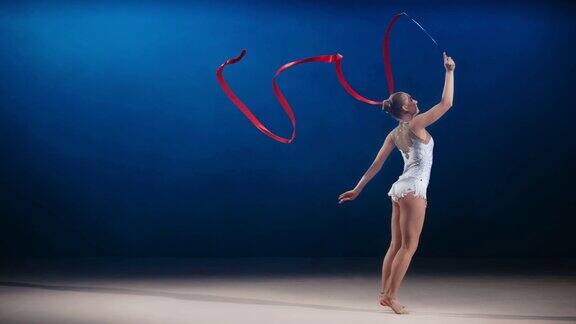 艺术体操运动员手持红丝带表演劈叉跳跃