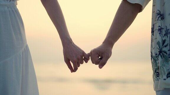 4K的亚洲情侣在夏日夕阳下的海滩上手牵着手