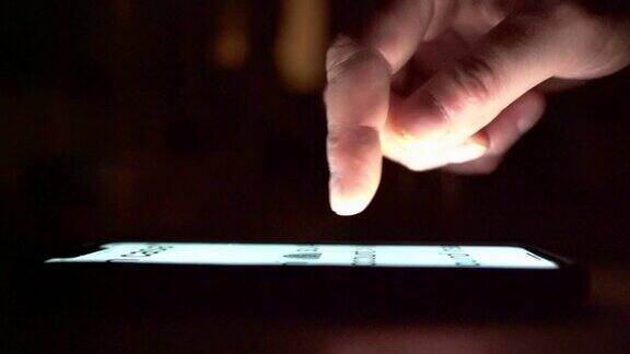 男性在夜晚使用手机和滚动的手特写