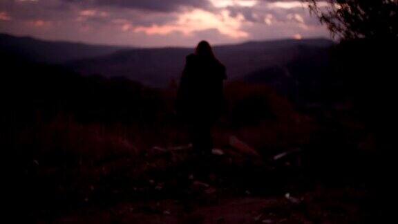 黄昏时分在山顶上举起双臂的女人