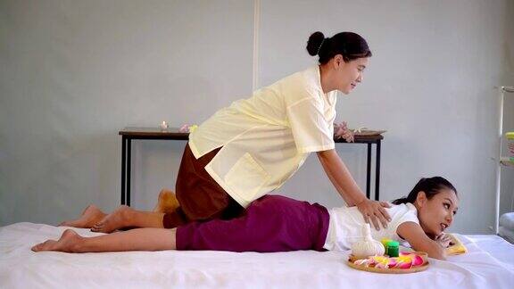 泰国按摩师正在泰国水疗中心用慢动作给一位女士进行背部按摩