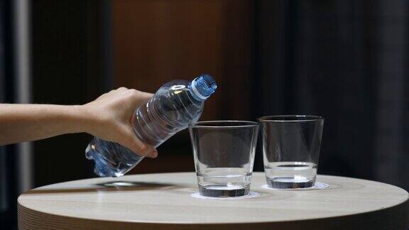 手握水瓶将水倒入玻璃杯中