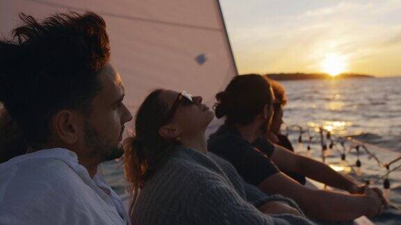 日落时分一群朋友在帆船甲板上享受微风