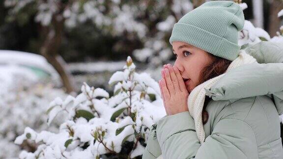 年轻的女子在寒冷的雪天在街上暖手