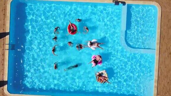 朋友们在游泳池里用充气火烈鸟天鹅床垫开派对的航拍阳光灿烂的日子里快乐的年轻人在豪华的度假胜地放松从以上观点穿着比基尼的女孩在阳光下晒日光浴