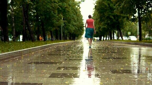 下雨的时候一个穿着蓝凉鞋的年轻女子走在公园的湿路上