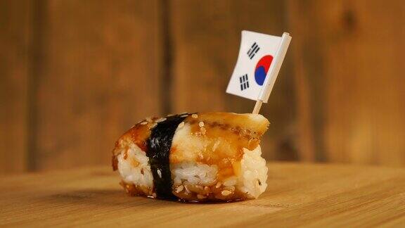 寿司上面有鱼、米饭、海藻和韩国小国旗在木制的转盘上旋转
