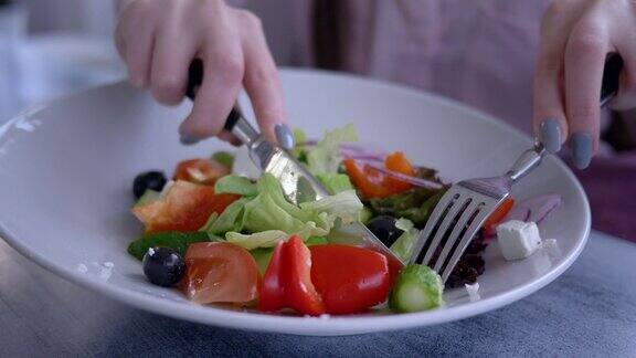 美丽的饮食食物女性用刀叉切希腊沙拉的新鲜黄瓜特写