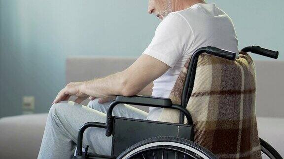 一位坐在轮椅上看着双腿点头的老人失去了行走的能力