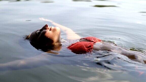 放松的年轻女子在比基尼漂浮在湖上