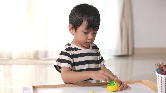 蹒跚学步的小男孩在玩粘土