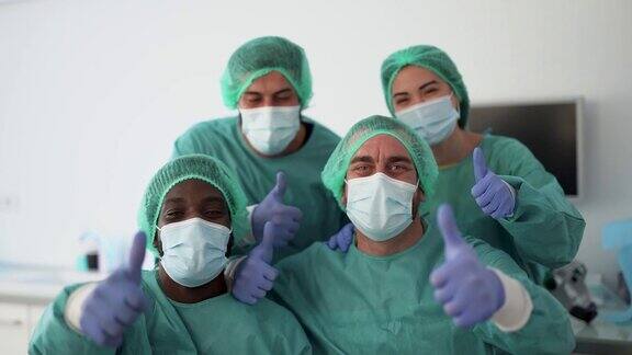 医生和护士竖起大拇指戴着外科口罩应对冠状病毒爆发医院里的医护人员穿着防护服