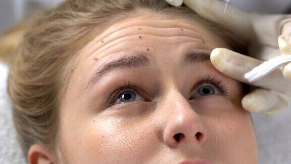 美容师注射透明质酸液体在女性额头的皱纹瑕疵