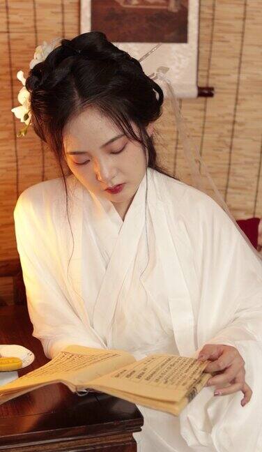 一位身着汉服的中国古代美女正在阅读书籍和竹简