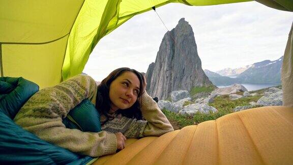 一名妇女躺在Senja岛的帐篷里可以看到山上的景色