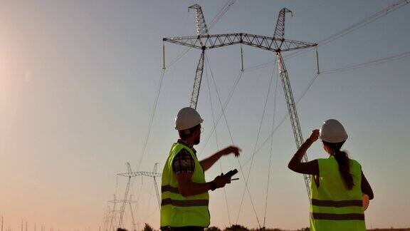 夕阳西下两位电气工程师在高压电塔的背景下见面握手工人在电网附近开会团队合作签约签约生意人慢动作
