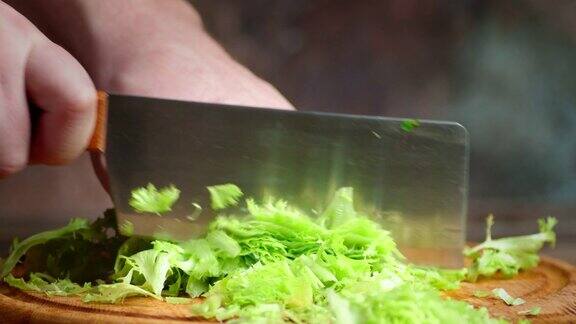男性的手在切菜板上用一把大刀切莴苣