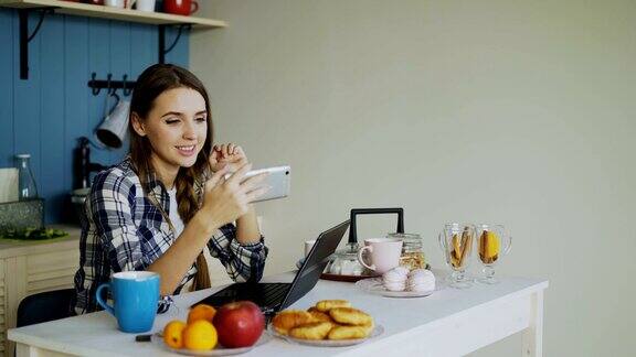 在厨房里用智能手机在线视频聊天的快乐微笑的女人