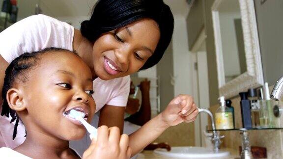 母亲教她的女儿在浴室刷牙4k