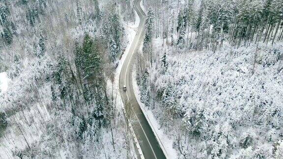 一辆汽车正行驶在冬天的林间山路上德国阿尔卑斯山的雪景无人机航拍视频